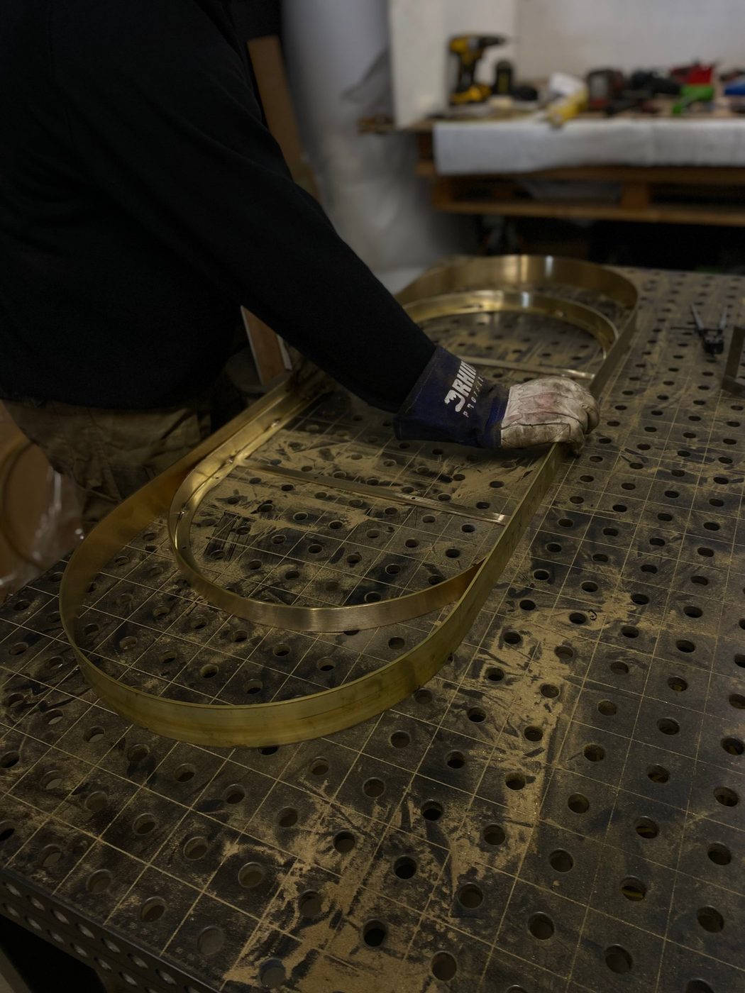 A brass frame laid out on the workshop table