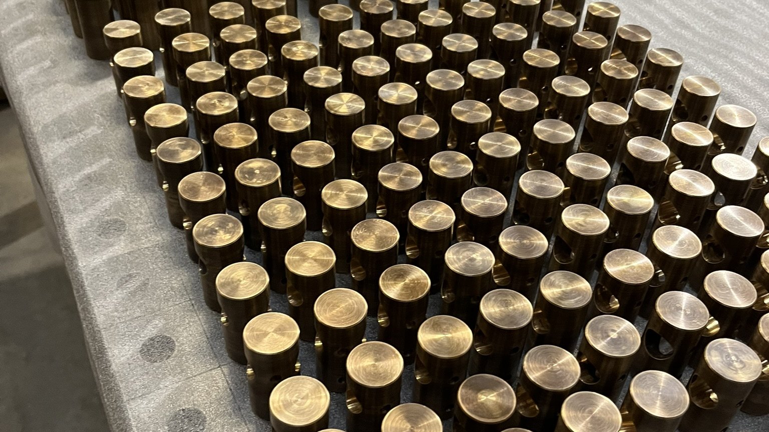Rows of freshly turned brass connectors on the workshop bench